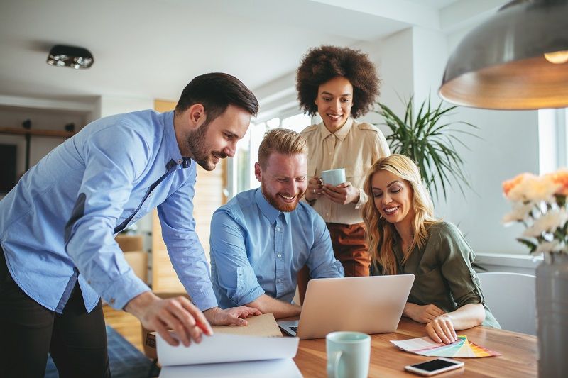 Ein Team betrachtet während der gemeinsamen Arbeit den Bildschirm eines Laptops.