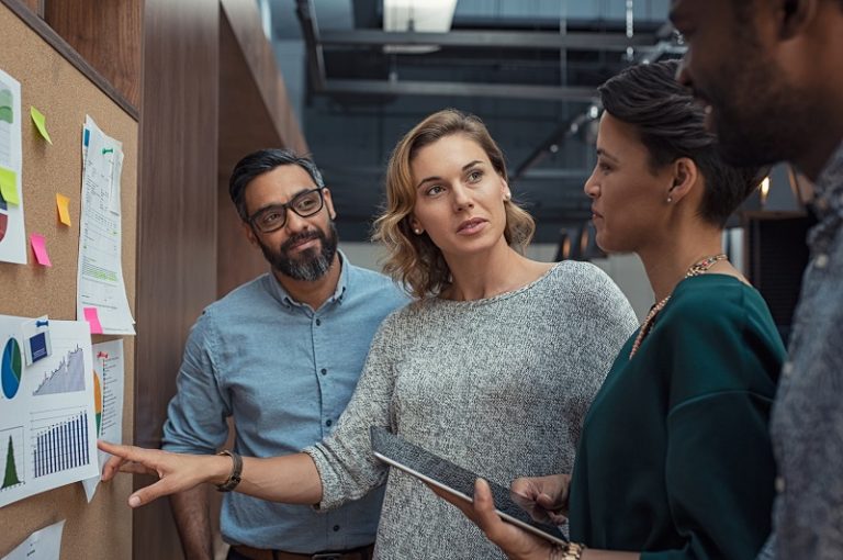 Eine Gruppe von Mitarbeitern diskutiert vor einer Pinnwand über das Thema Enterprise Content Management.