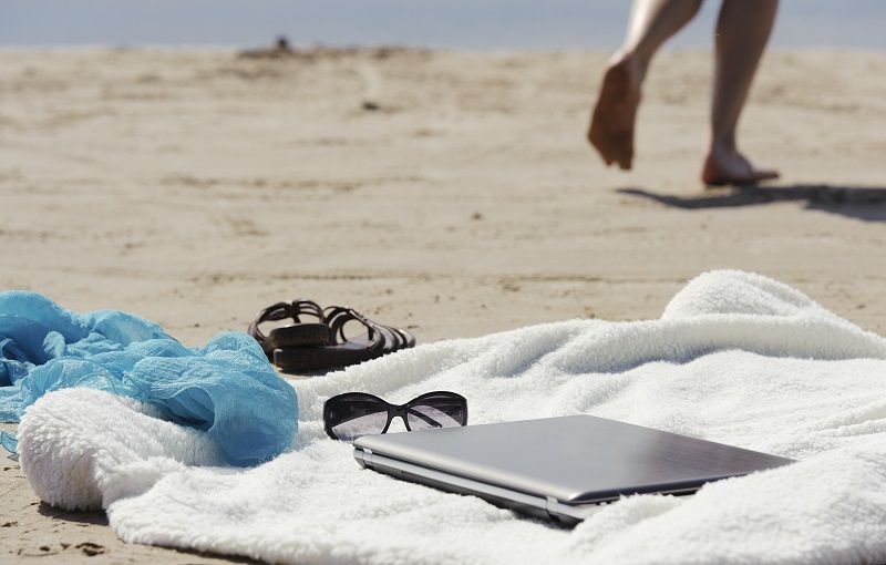 Eine Frau lässt ihren Laptop unbeaufsichtigt am Strand stehen.