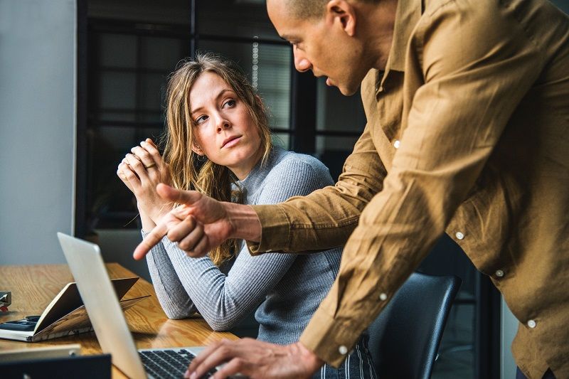 Zwei Kollegen unterhalten sich an einem Computer über Konzepte zur Zusammenarbeit in Unternehmen.