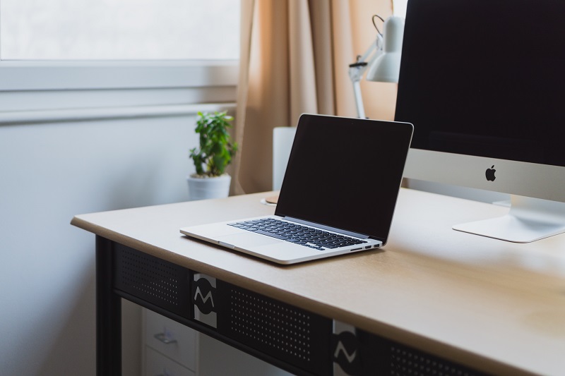 A laptop in front of a computer.